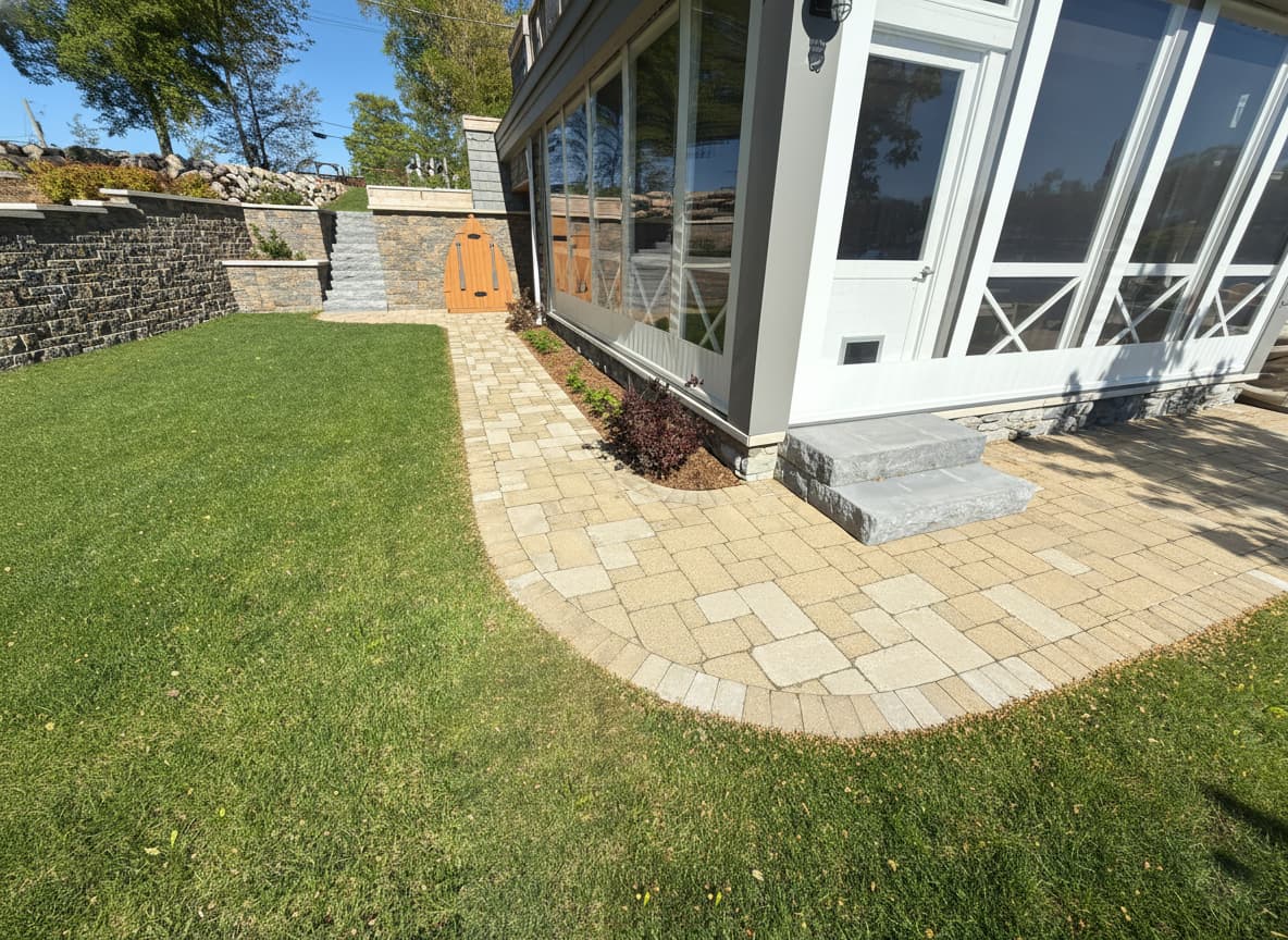 Paver patio alongside lakehouse sunroom with stone retaining wall, Southwest Michigan