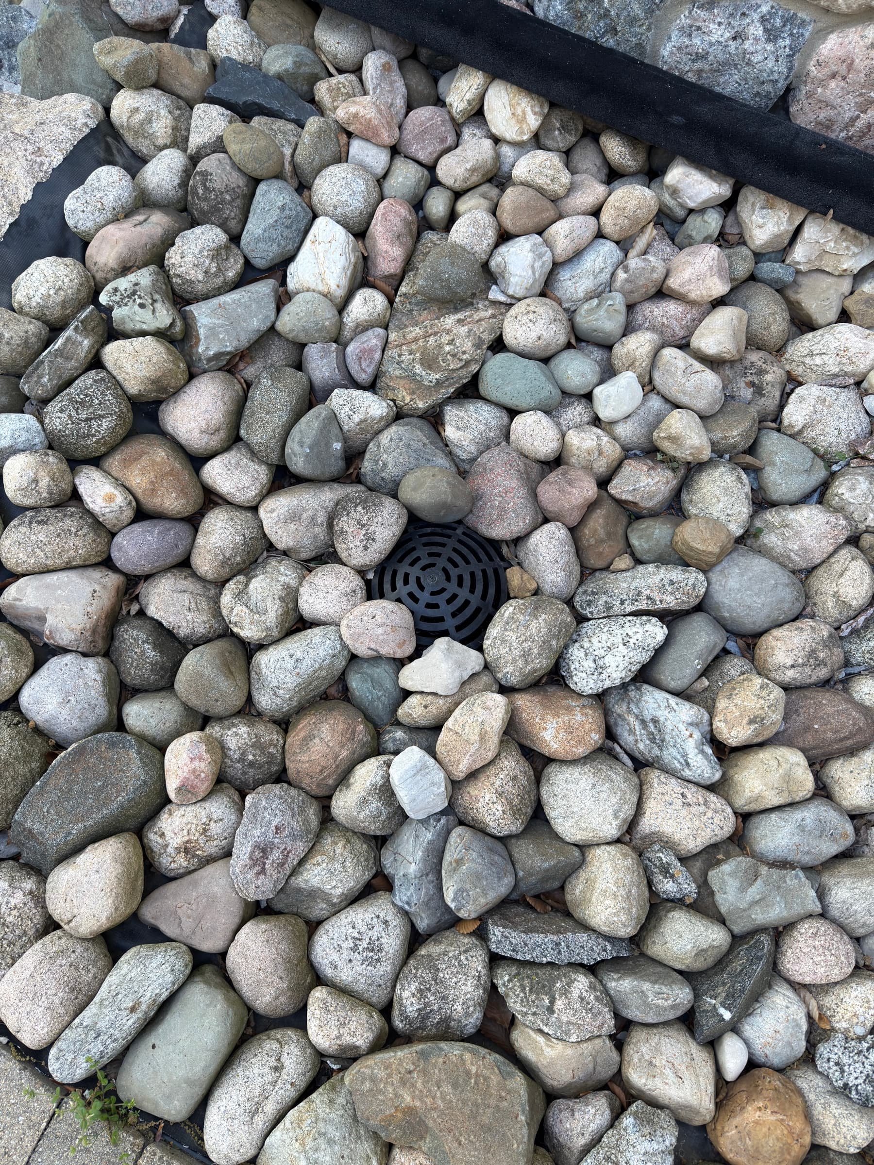 French drain concealed beneath river rock, Southwest Michigan drainage installation