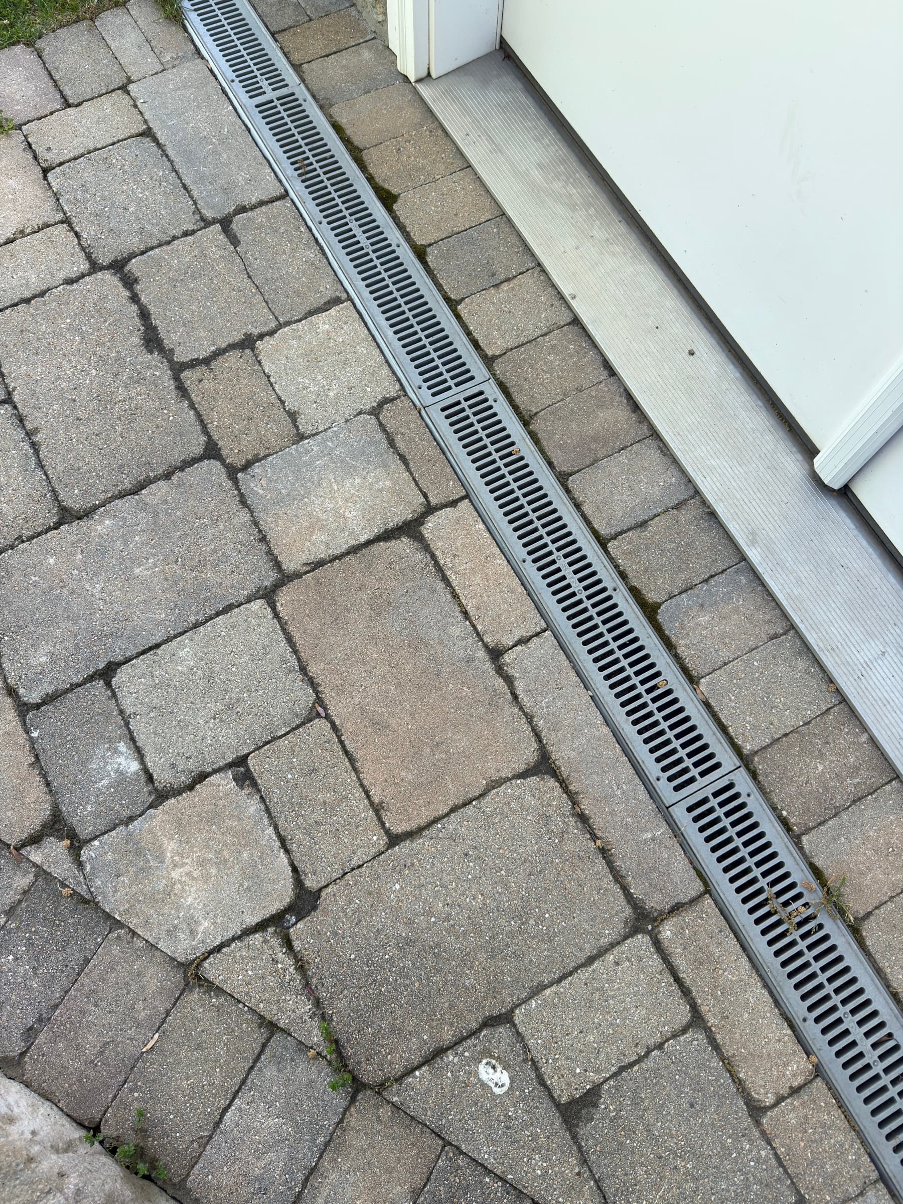 Linear drainage channel integrated into paver surface near building