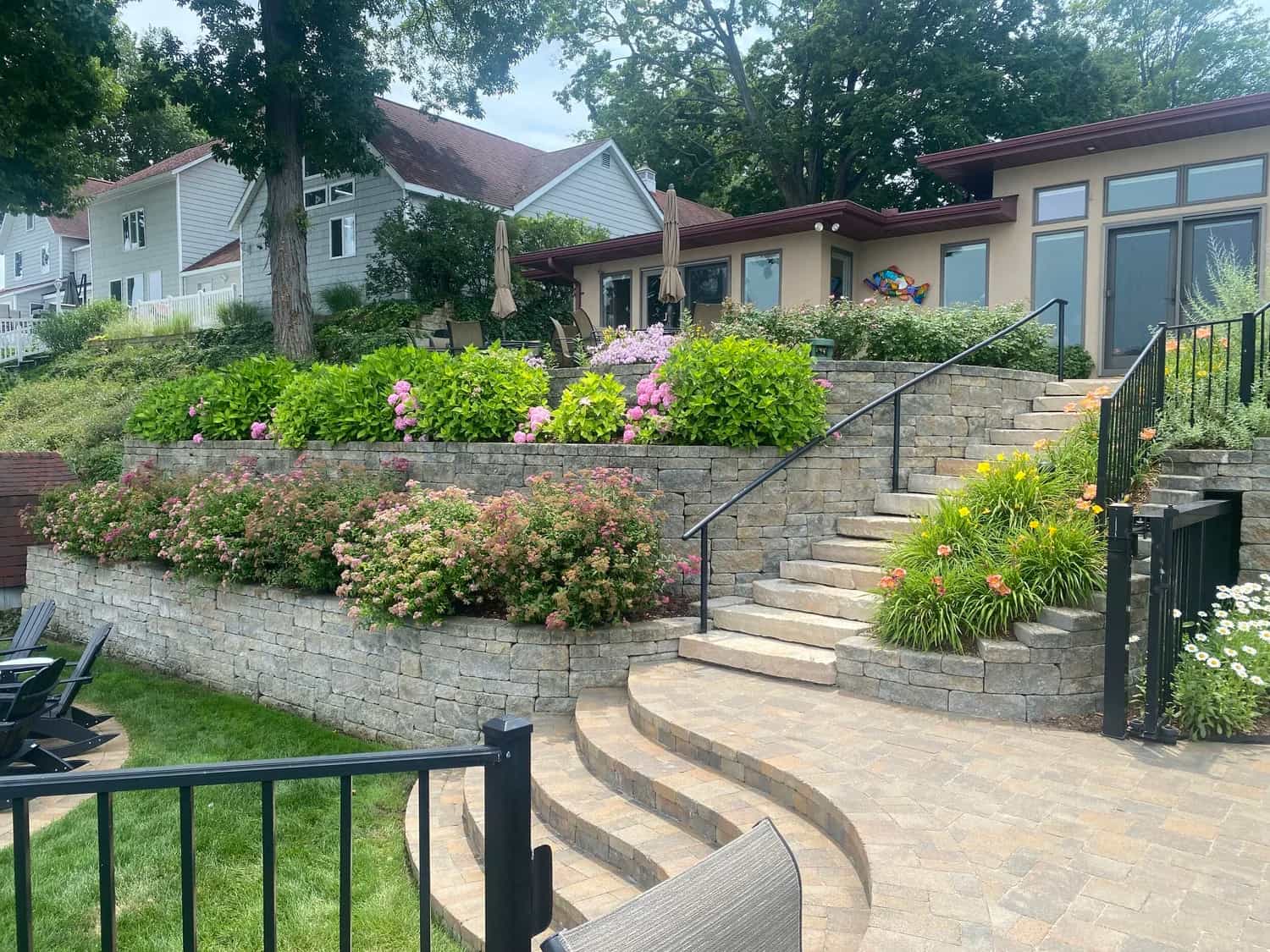 Tiered stone retaining wall with curved steps and blooming hydrangeas — MTL Landscaping craftsmanship, Southwest Michigan