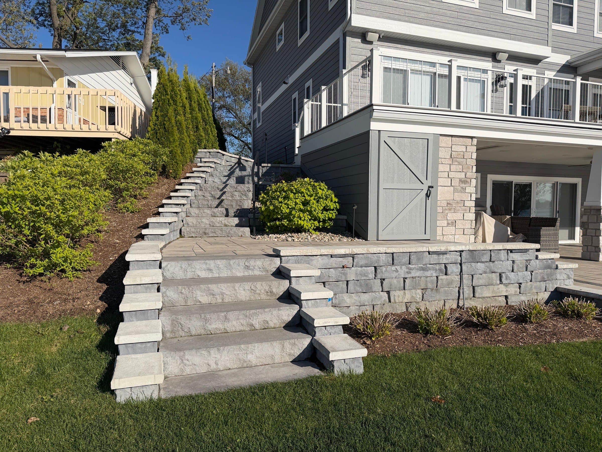 Grand stone steps with layered block retaining wall alongside a Southwest Michigan home