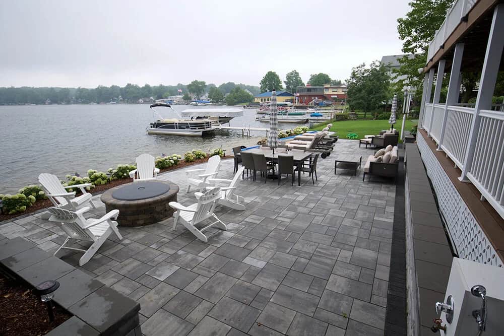Lakeside stone patio with fire pit and Adirondack chairs overlooking the water